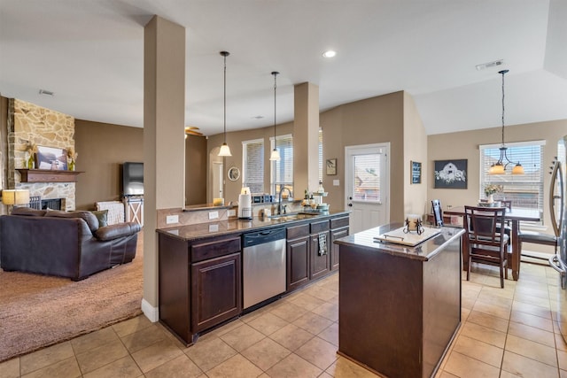 kitchen with a fireplace, a sink, visible vents, dishwasher, and a center island with sink