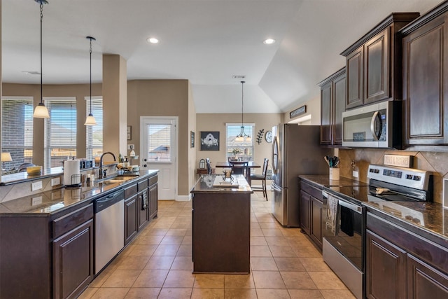 kitchen with stainless steel appliances, an island with sink, a sink, and dark brown cabinetry