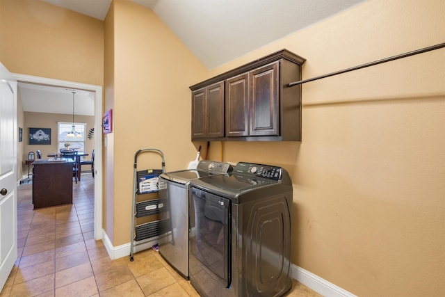 clothes washing area with baseboards, cabinet space, washing machine and clothes dryer, and light tile patterned floors