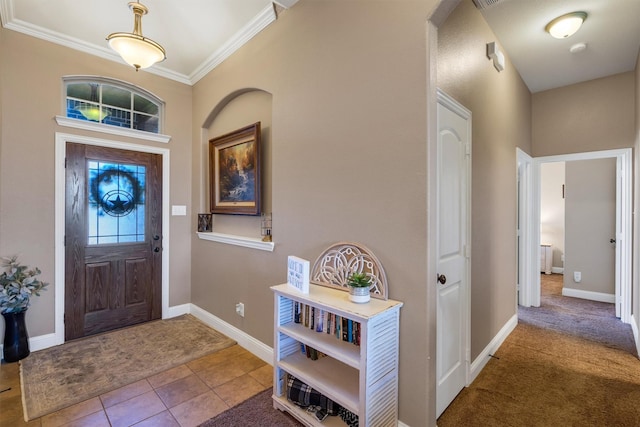 tiled foyer featuring ornamental molding, carpet, and baseboards