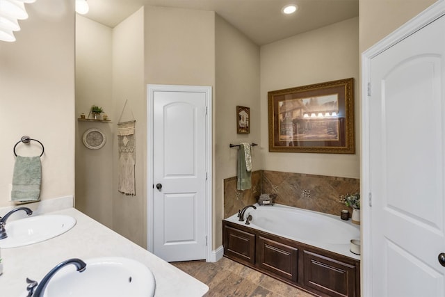 bathroom featuring a garden tub, double vanity, wood finished floors, and a sink