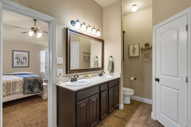 full bath featuring double vanity, a sink, toilet, and a ceiling fan