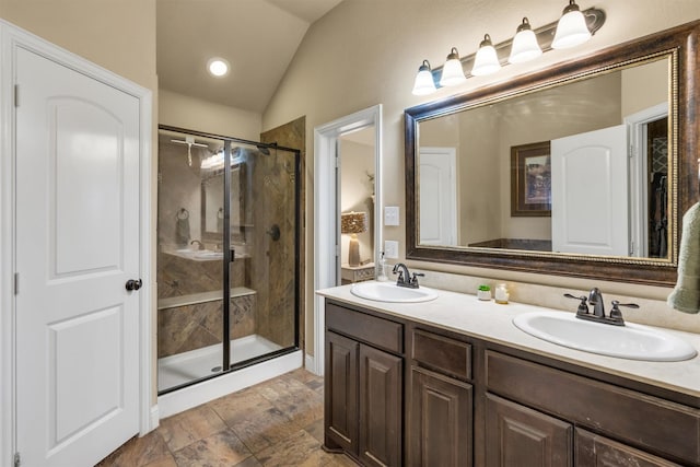 full bathroom with lofted ceiling, a sink, a shower stall, and double vanity