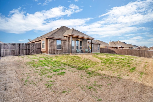 back of property with a yard, a fenced backyard, and brick siding