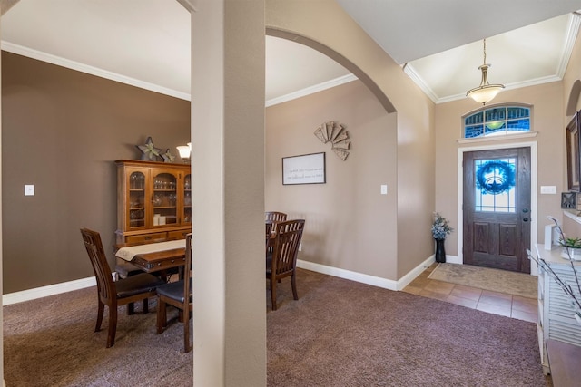 carpeted entrance foyer with arched walkways, ornamental molding, tile patterned flooring, and baseboards