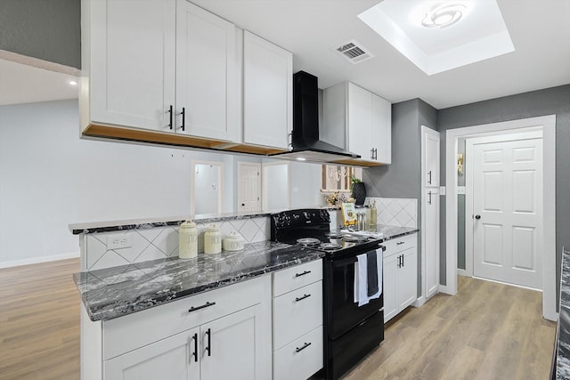 kitchen with light wood-style flooring, visible vents, white cabinetry, black electric range, and wall chimney exhaust hood