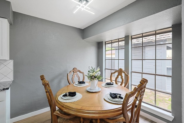 dining space featuring a textured wall, wood finished floors, and baseboards