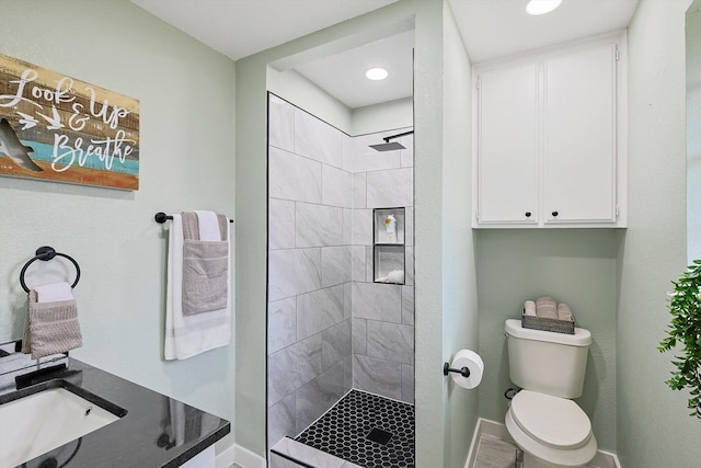 full bathroom with toilet, baseboards, a tile shower, and a sink