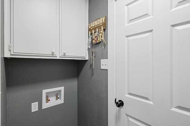 laundry area featuring hookup for a washing machine, cabinet space, and a textured wall