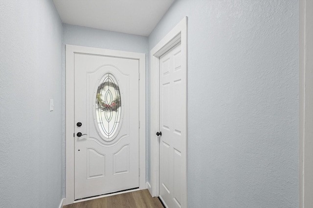 entryway featuring dark wood-style flooring and a textured wall