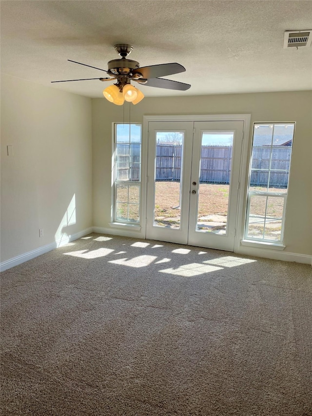 empty room with a textured ceiling, visible vents, baseboards, french doors, and carpet