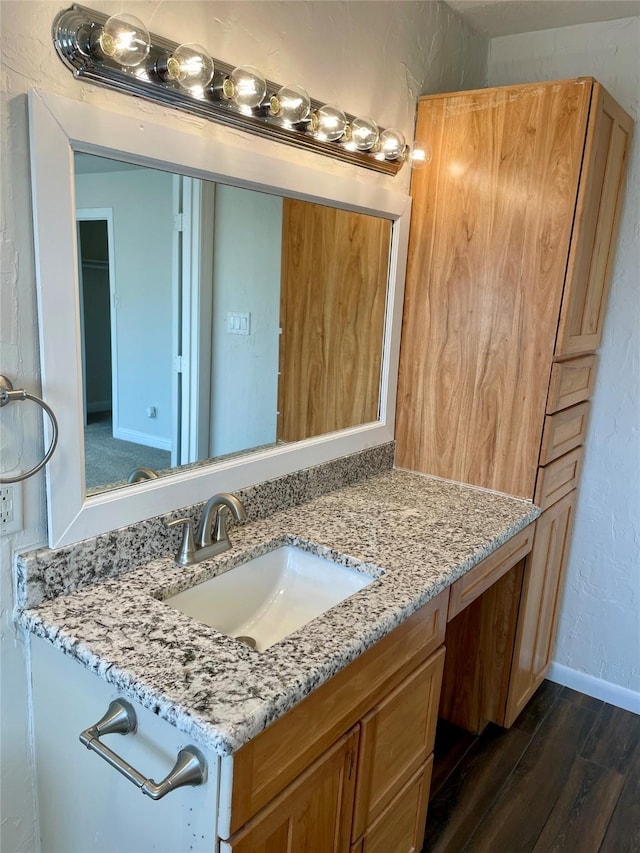 bathroom featuring a textured wall, baseboards, wood finished floors, and vanity