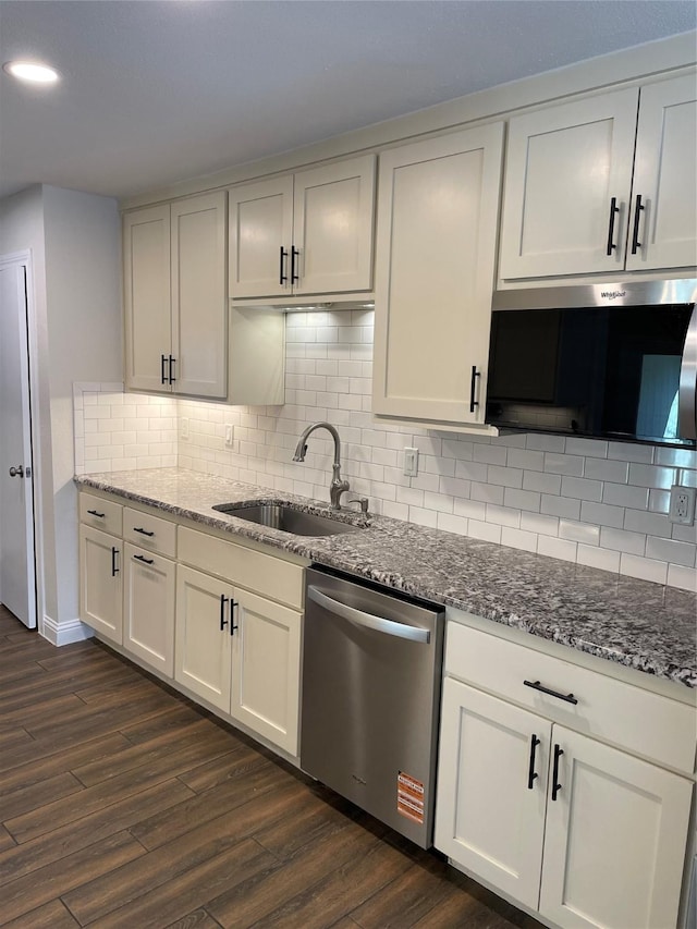 kitchen with stainless steel appliances, stone countertops, a sink, and dark wood-style floors