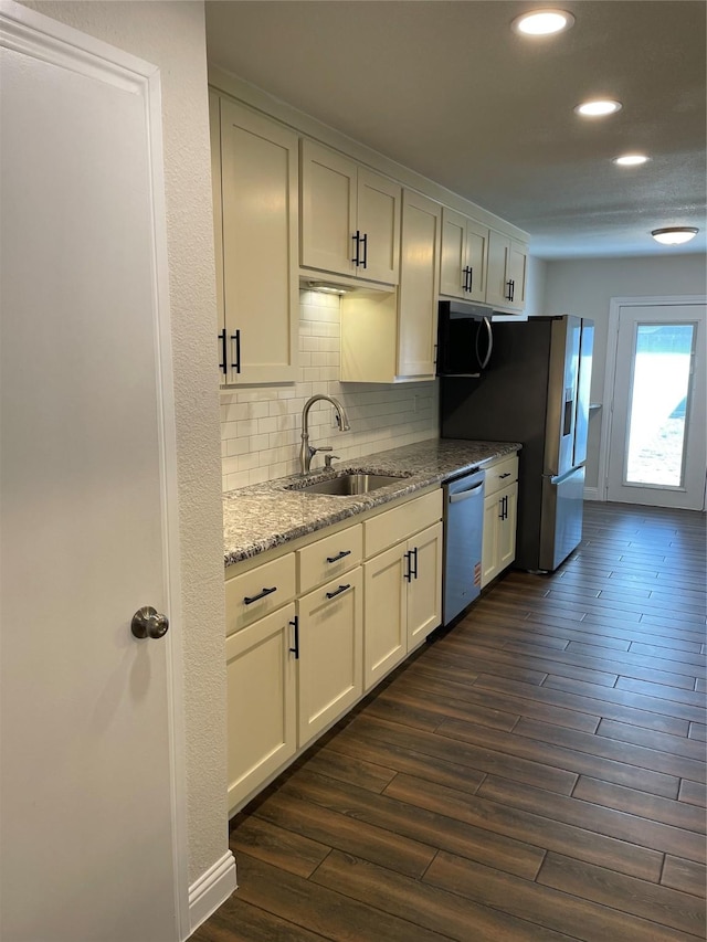 kitchen with stainless steel appliances, tasteful backsplash, a sink, and dark wood finished floors