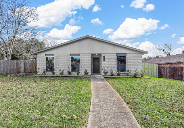 view of front facade with a front lawn, fence, and brick siding