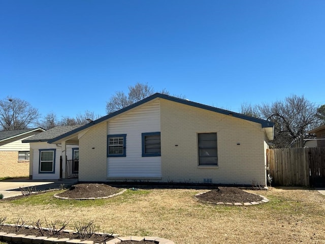 view of front of home featuring brick siding, fence, a front lawn, and a patio