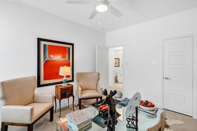 sitting room featuring ceiling fan and baseboards