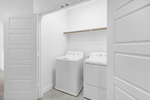 laundry area with light tile patterned floors, laundry area, independent washer and dryer, and baseboards