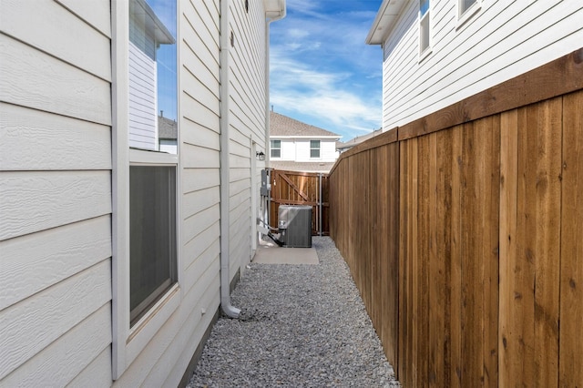 view of property exterior with a gate, fence, and central AC