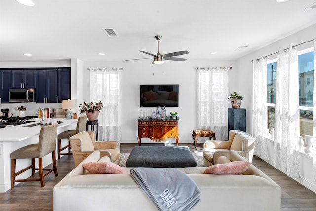 living area with dark wood-type flooring, a ceiling fan, visible vents, and recessed lighting