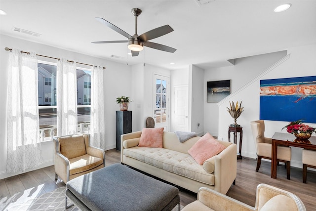 living room with light wood-style floors, a wealth of natural light, visible vents, and a ceiling fan