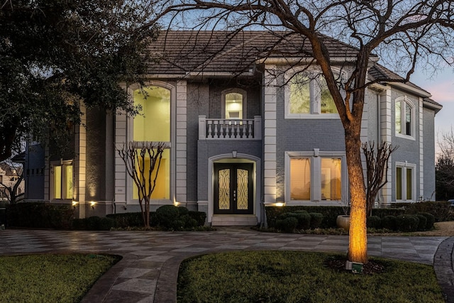 view of front of property featuring a balcony, brick siding, and french doors