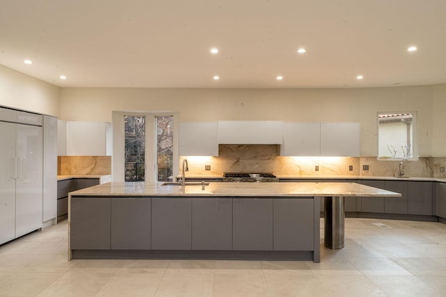 kitchen featuring a spacious island, gray cabinets, stove, white cabinetry, and a sink