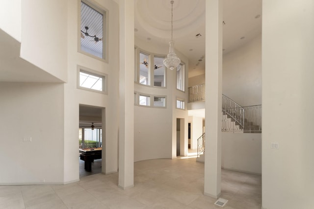 interior space featuring billiards, visible vents, a high ceiling, stairs, and a chandelier