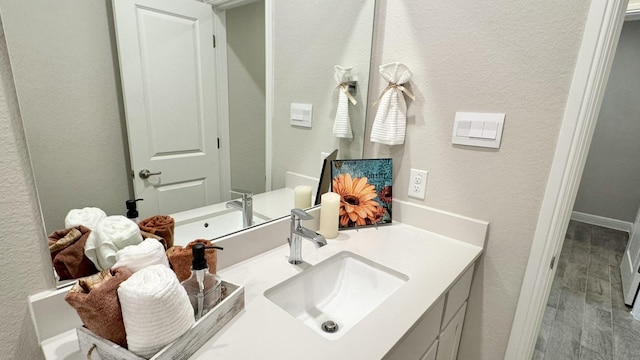 bathroom featuring vanity, wood finished floors, and a textured wall