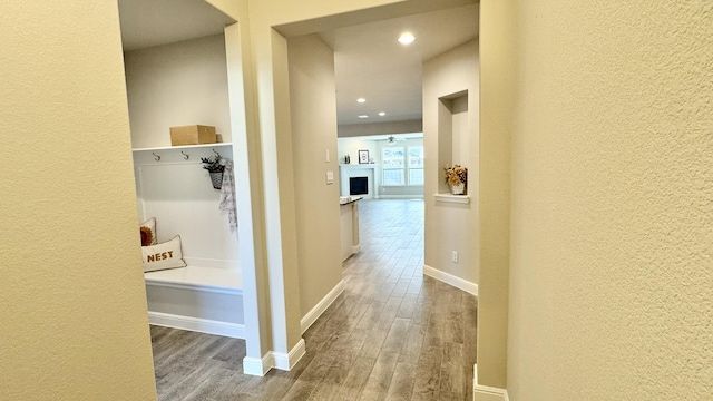 corridor with a textured wall, wood finished floors, and baseboards