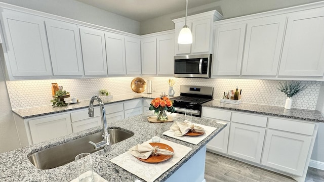 kitchen with appliances with stainless steel finishes, a sink, white cabinets, and decorative backsplash