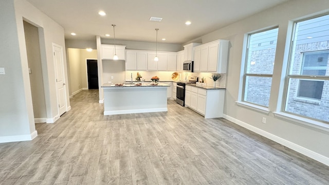 kitchen with stainless steel appliances, white cabinets, light wood-style flooring, and tasteful backsplash