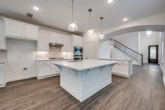 2009 Dappled Grey Ave, Aubrey, TX 76227 - kitchen featuring arched walkways, white cabinetry, a center island with sink, light countertops, and recessed lighting