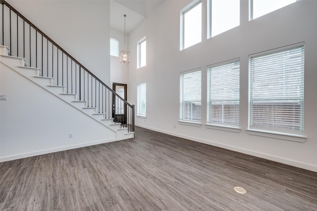 2009 Dappled Grey Ave, Aubrey, TX 76227 - unfurnished living room featuring wood finished floors, a towering ceiling, stairway, and a chandelier