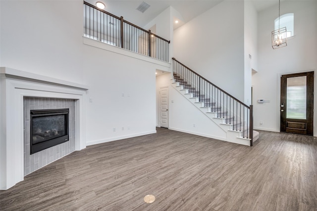 2009 Dappled Grey Ave, Aubrey, TX 76227 - unfurnished living room with stairs, wood finished floors, a high ceiling, a chandelier, and a fireplace