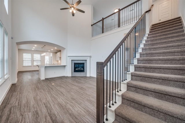 2009 Dappled Grey Ave, Aubrey, TX 76227 - stairs with wood finished floors, ceiling fan, a towering ceiling, arched walkways, and a fireplace