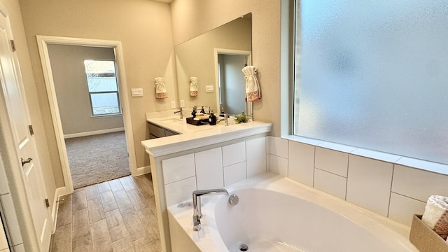 bathroom with baseboards, vanity, a bath, and wood tiled floor