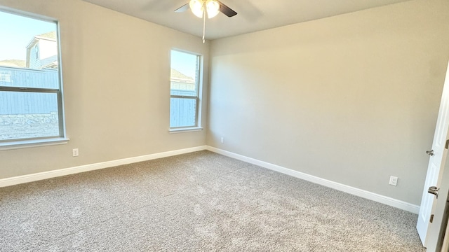 carpeted empty room with ceiling fan and baseboards