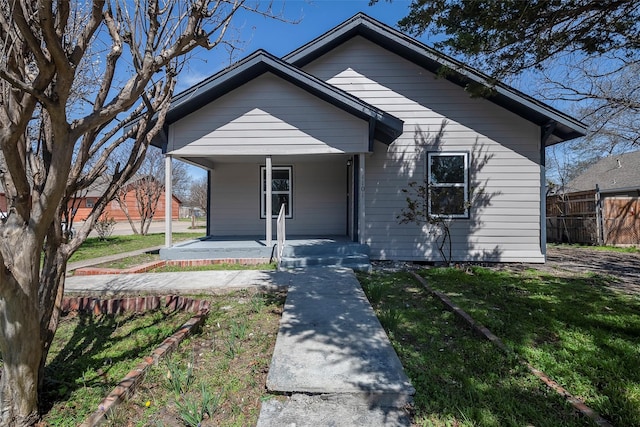 bungalow-style home with a porch, a front lawn, and fence