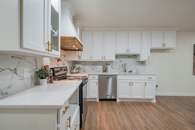 kitchen featuring premium range hood, light wood-style flooring, a sink, white cabinetry, and appliances with stainless steel finishes