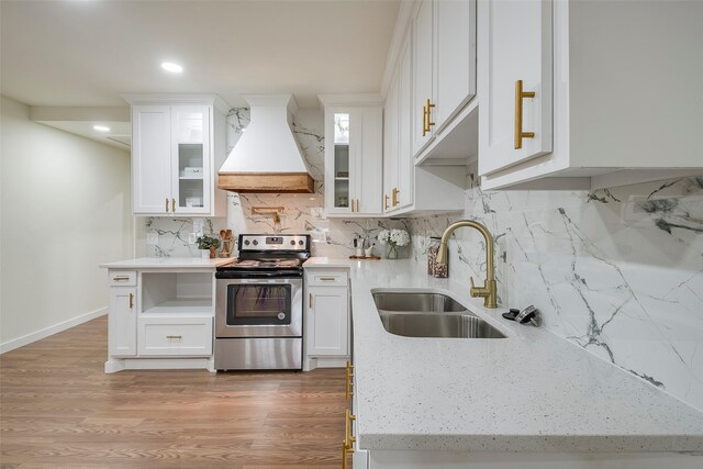 kitchen featuring electric range, custom range hood, a sink, wood finished floors, and white cabinetry