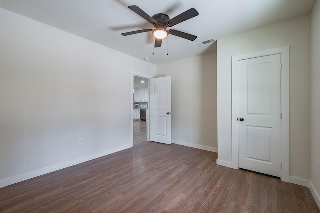 unfurnished bedroom with a ceiling fan, dark wood-type flooring, baseboards, and visible vents