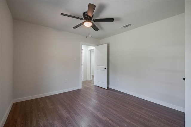 spare room featuring ceiling fan, visible vents, baseboards, and dark wood-style floors