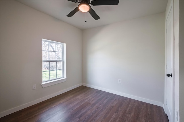 empty room featuring dark wood-type flooring, a ceiling fan, and baseboards