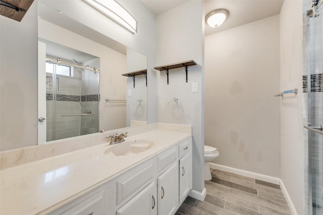 bathroom featuring baseboards, toilet, vanity, wood finish floors, and a shower stall