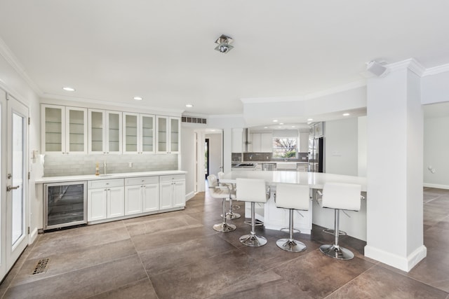 kitchen featuring wine cooler, visible vents, white cabinets, a kitchen breakfast bar, and stainless steel fridge