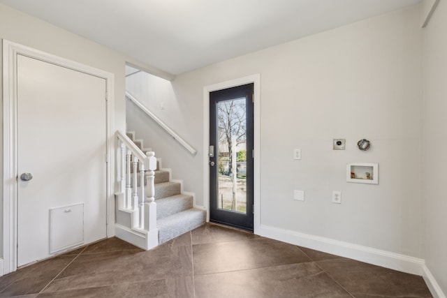 entryway with baseboards, concrete floors, and stairway