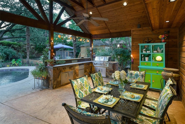 view of patio featuring grilling area, outdoor dining space, ceiling fan, exterior kitchen, and a fenced backyard