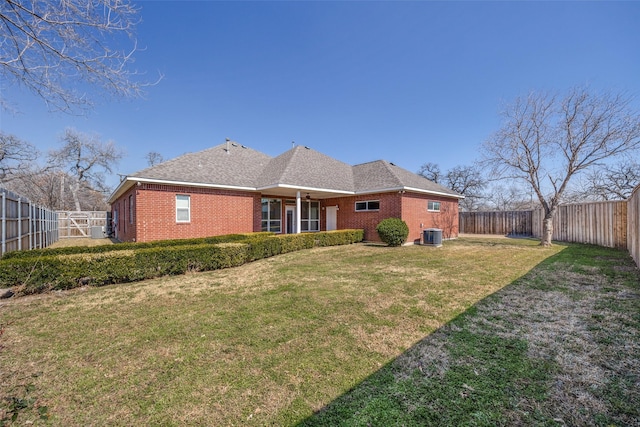 rear view of property featuring cooling unit, brick siding, a lawn, and a fenced backyard