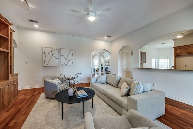 living area with dark wood-style floors, ornamental molding, visible vents, and baseboards